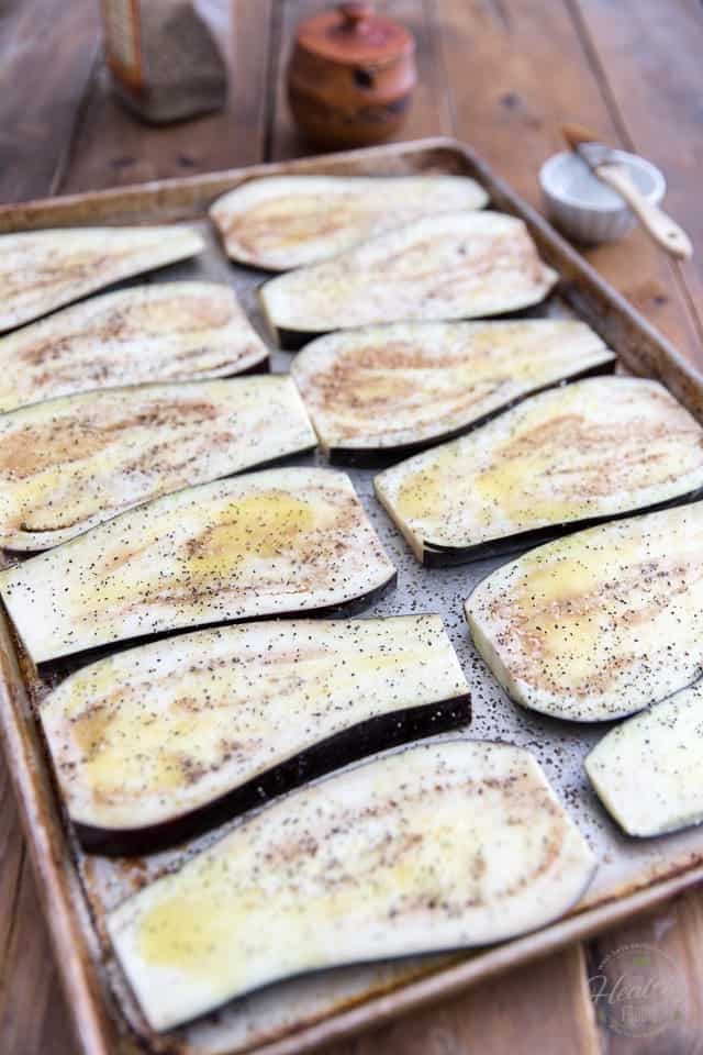 Eggplant slices arranged on large baking sheet, brushed with olive oil and seasoned with salt and pepper
