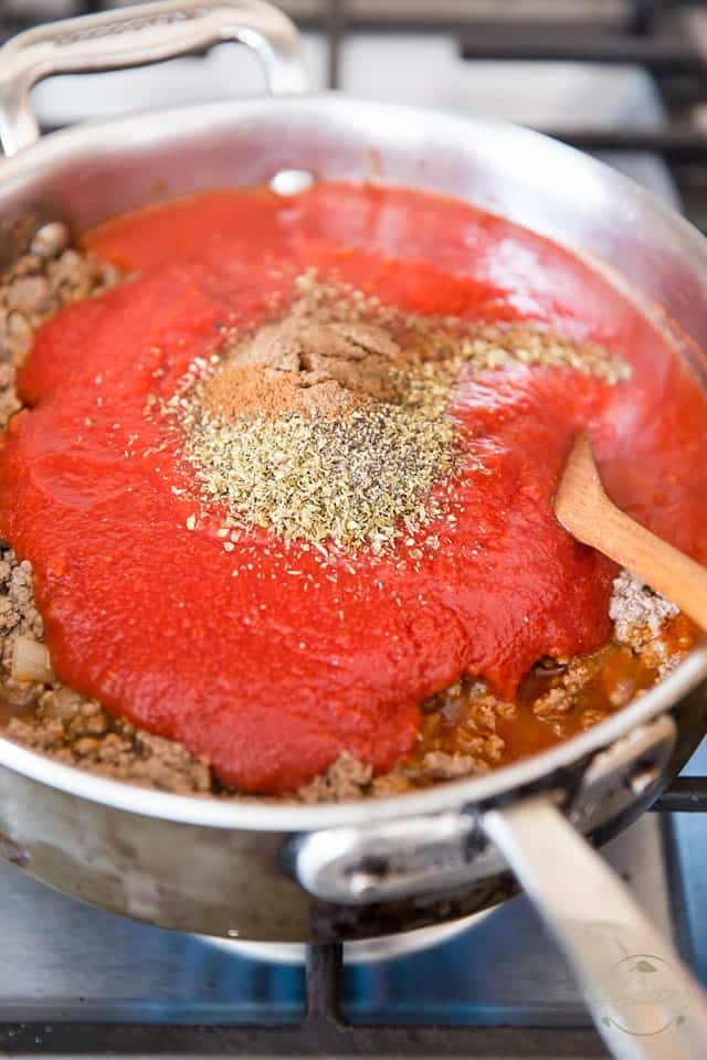 Crushed tomatoes go in with the meat in the saute pan, along with water and seasonings