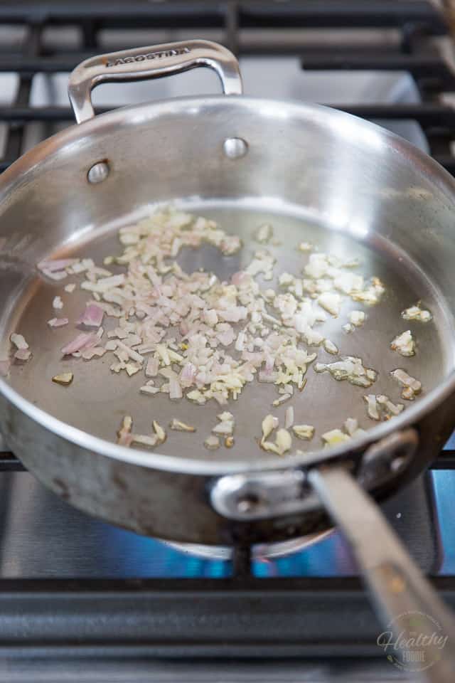 Onions and shallots cooking in a stainless steel saute pan