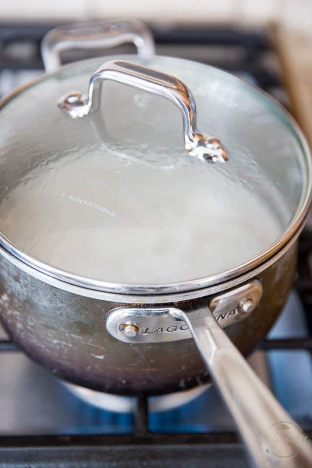 A saucepan on the stove top with a clear tempered glass lid on