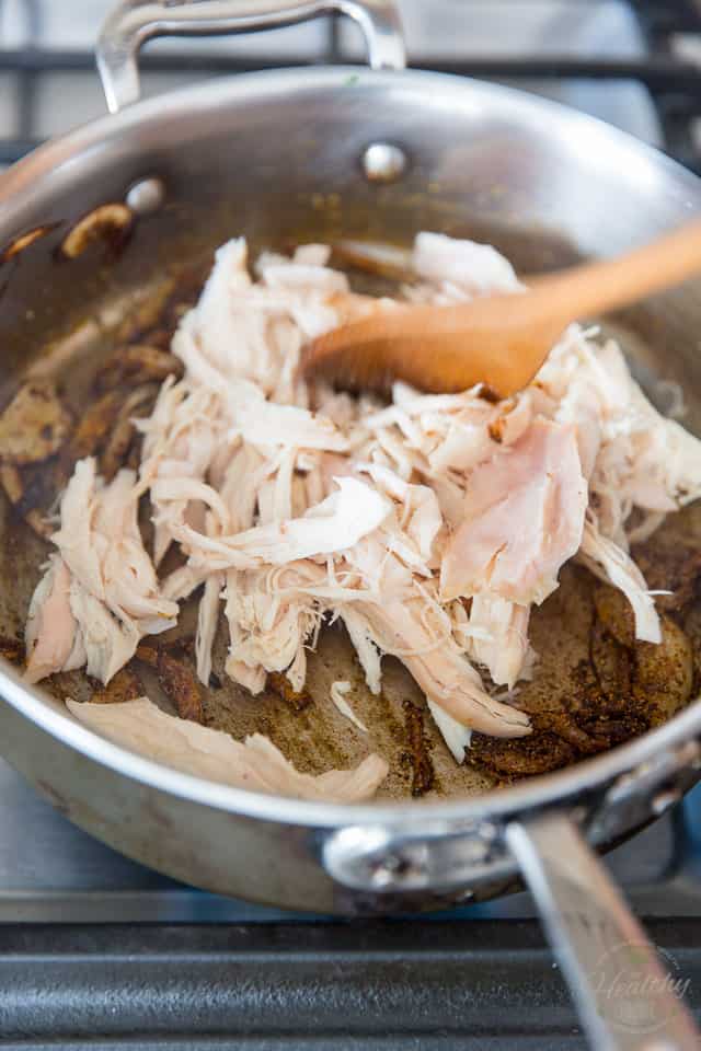 Shredded chicken in a stainless steel saute pan