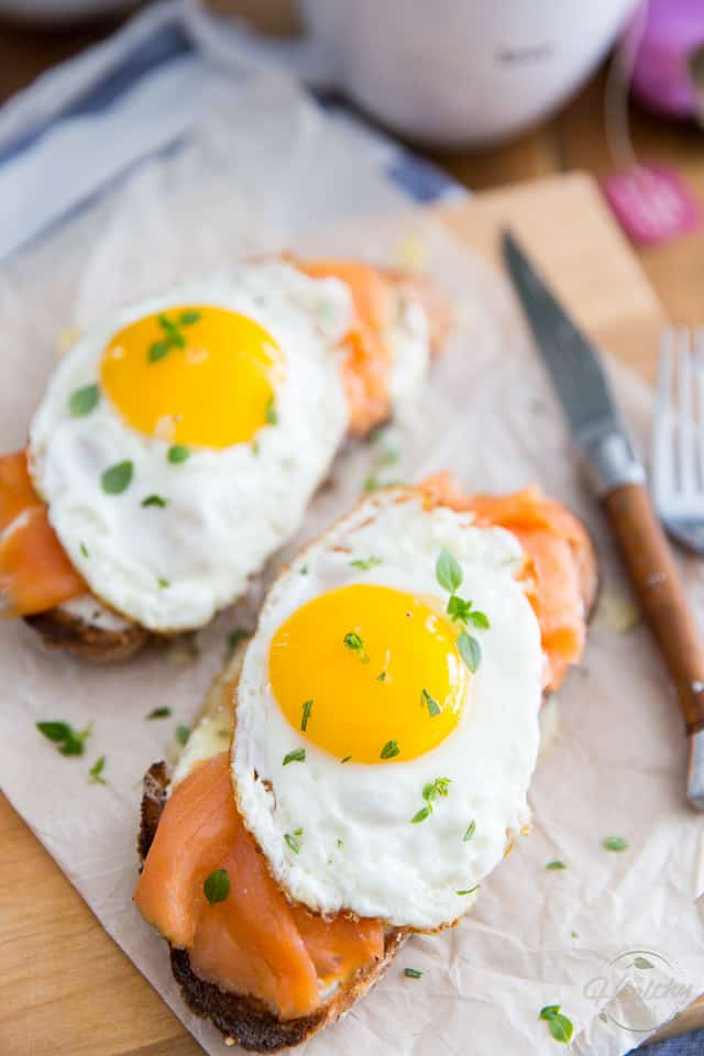 Smoked Salmon and Sharp Cheddar Croque-Madame on a wooden cutting board lined with parchment paper
