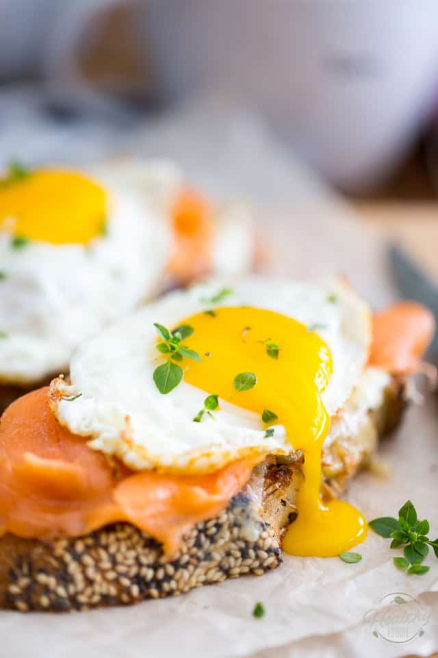 Smoked Salmon and Sharp Cheddar Croque-Madame on a wooden cutting board lined with parchment paper