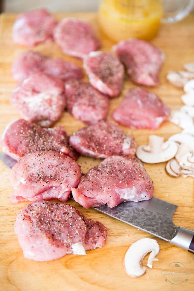 Pork medallions seasoned with salt and pepper, on a wooden cutting board with a knife under them