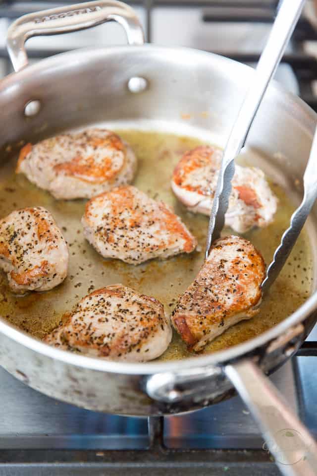 Pork medallions browning in a stainless steel saute pan