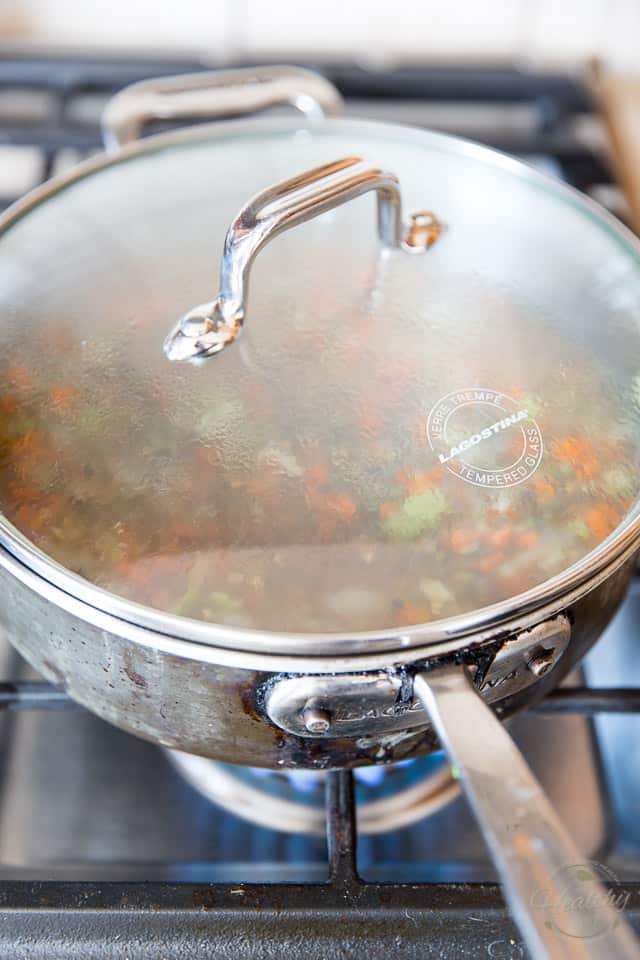 A saute pan with a clear glass lid on it