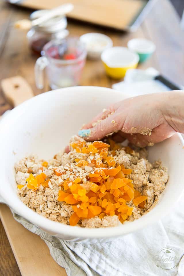Chopped apricots and almonds are being added to scones dough and mixed with one hand
