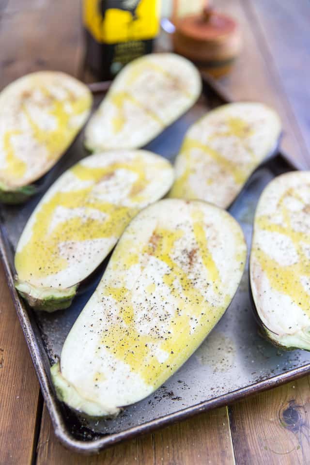 Eggplants sliced in half lengthwise arranged in a baking sheet cut face up, drizzled with olive oil and seasoned with salt and pepper