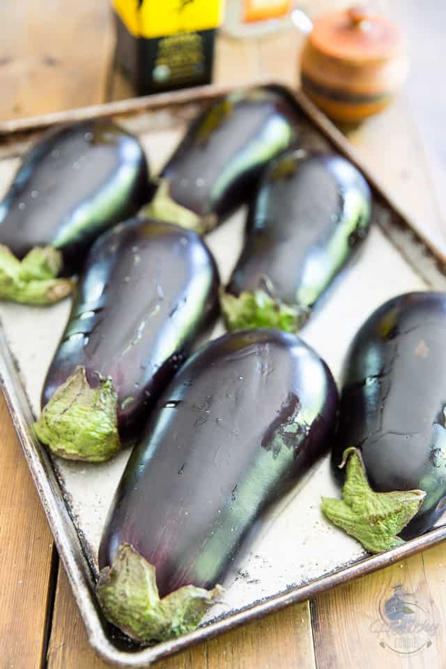 Eggplants sliced in half lengthwise arranged in a baking sheet cut face down