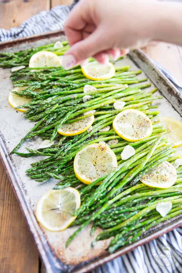 Asparagus with slices of lemon and garlic in an aluminum baking sheet