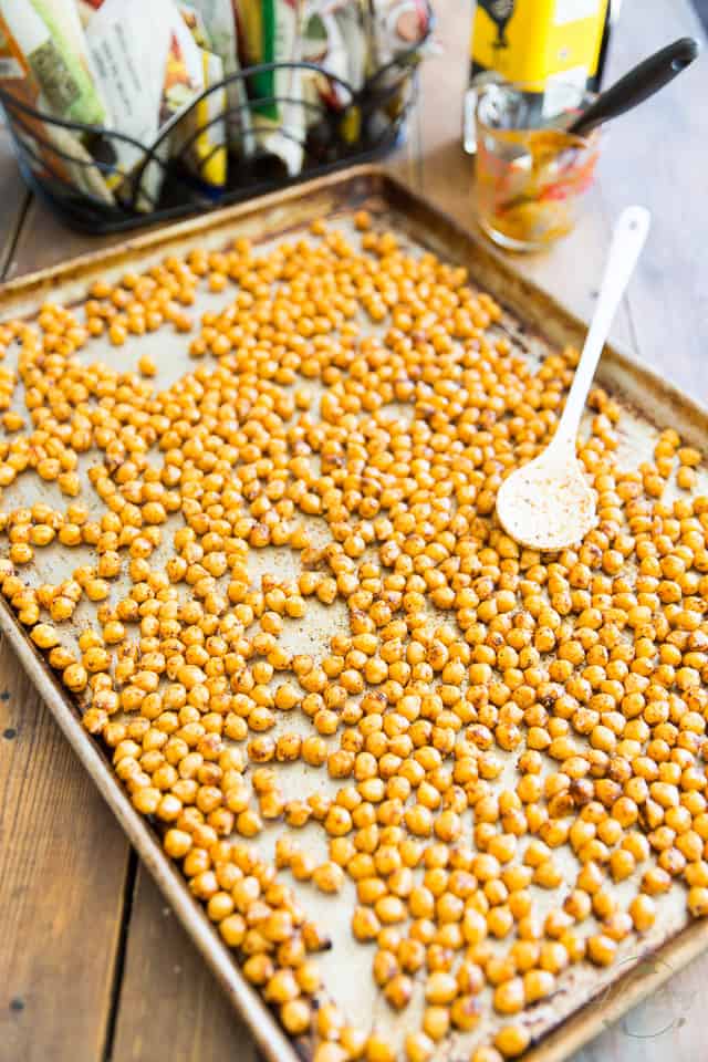 Seasoned chickpeas spread in a single layer on a large baking sheet