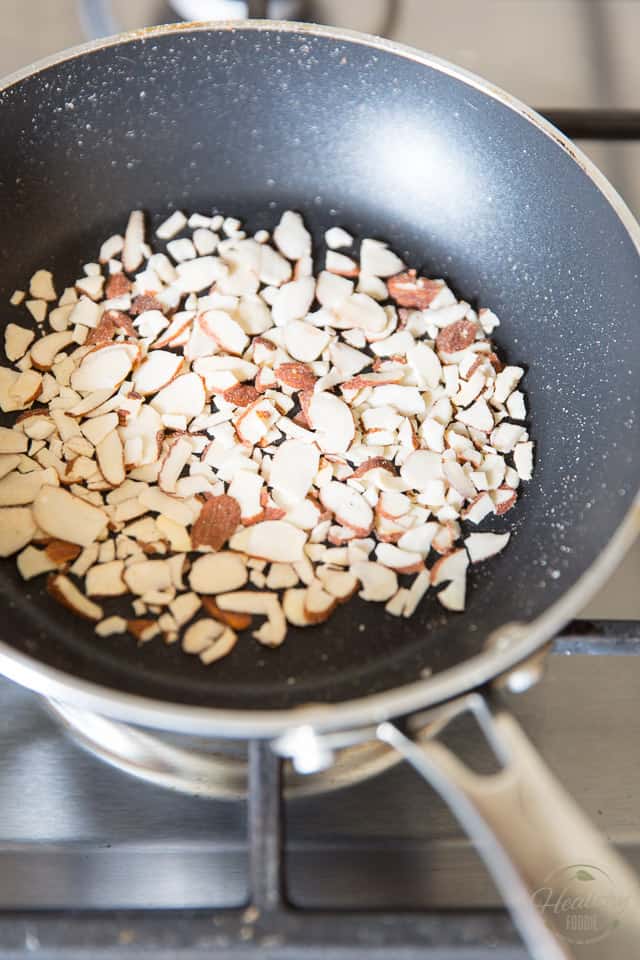 Sliced almonds toasting in a small non-stick skillet