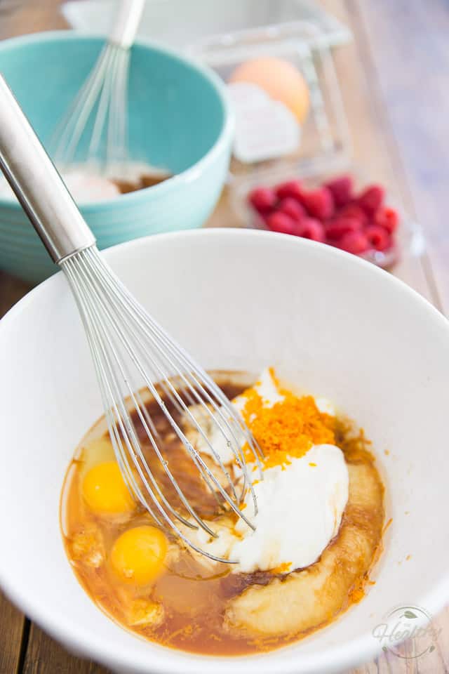 Overhead view of a bowl containing eggs, bananas, yogurt and orange zest, with a whisk resting on its side