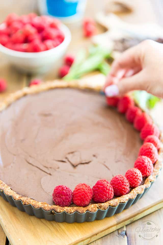 Chocolate pie getting topped with fresh raspberries