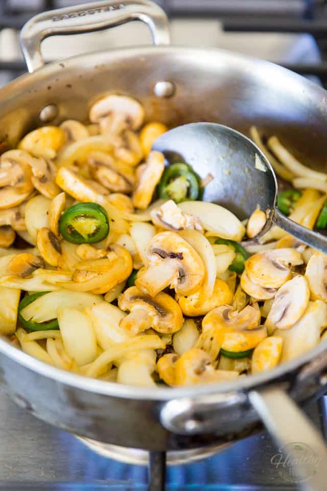 Onions, mushrooms and jalapeno peppers cooking in a stainless steel saute pan