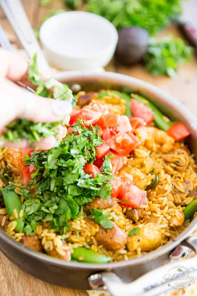 Tomatoes and cilantro are being added to Spanish Rice Casserole in a saute pan