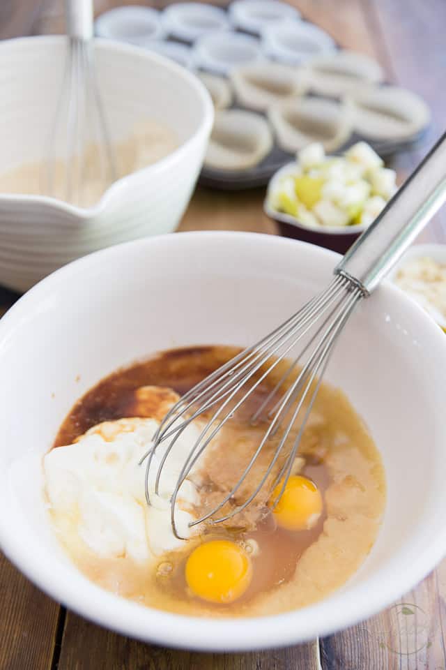 Eggs, yogurt, pureed pear, honey and vanilla extract in a white ceramic bowl with whisk sticking out on right hand side