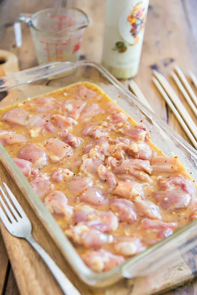Pieces of raw chicken marinating in a glass baking pan