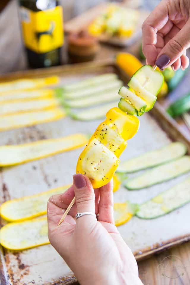 Thin slices of zucchini getting threaded onto wooden skewers