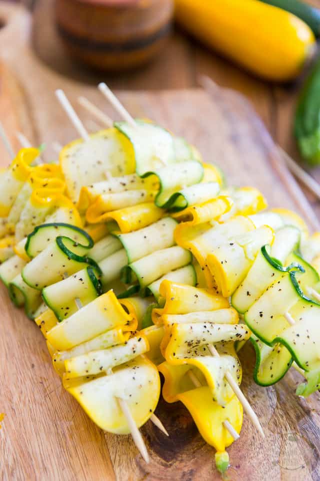 A pile of raw Zucchini Ribbon Skewers on a wooden board