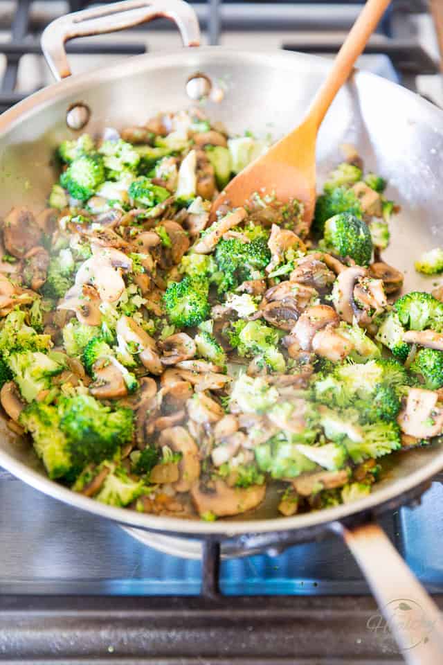 Broccoli, mushrooms and onions cooking in stainless steel skillet