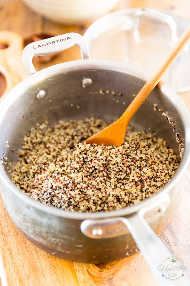 Cooked tricolor quinoa in saucepan with wooden spoon sticking out