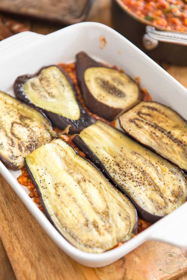 Vegetarian moussaka in the making - layering eggplant and sauce in a lasagna dish