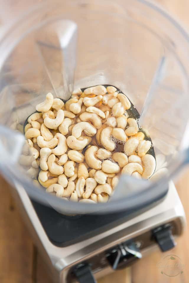 Cashews and maple syrup in the container of a food processor
