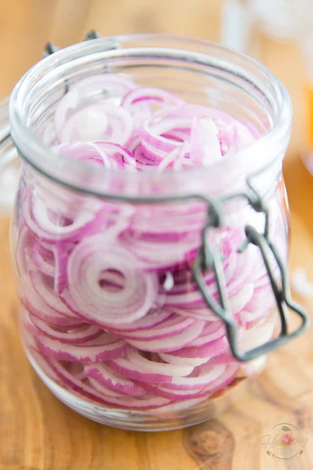 Place the sliced onions, garlic and peppercorns in a glass jar