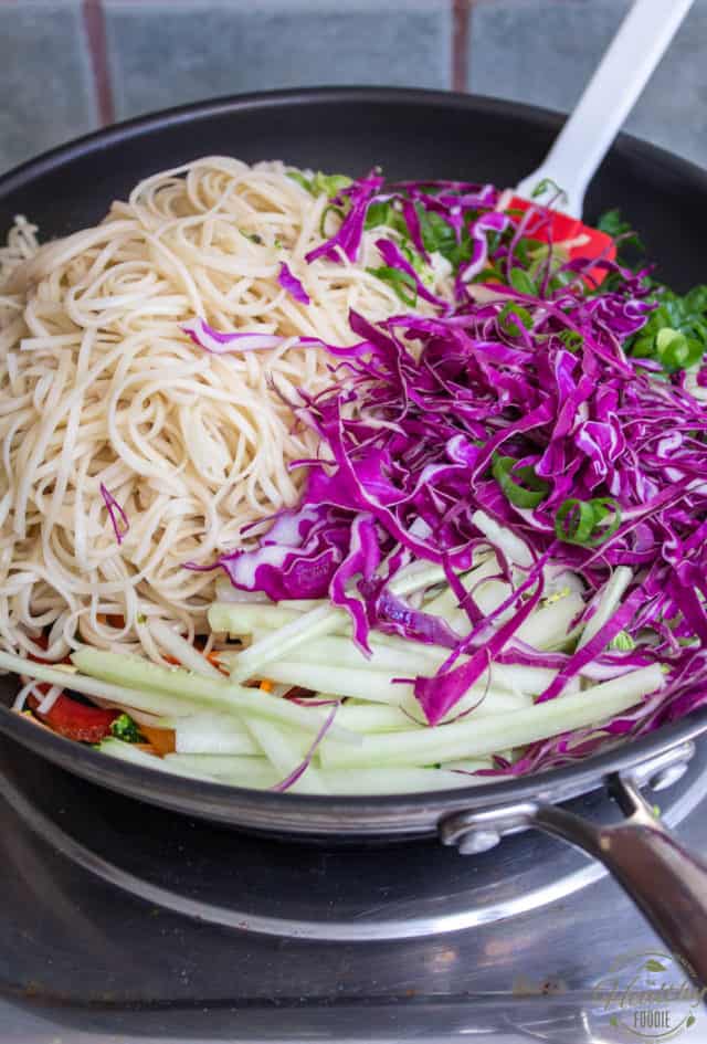 Add the drained noodles, cabbage, cucumber and green onions to the pan