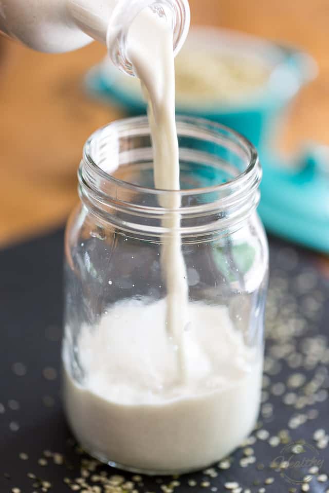 Milk being poured from bottle to glass jar