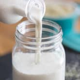 Milk being poured from bottle to glass jar
